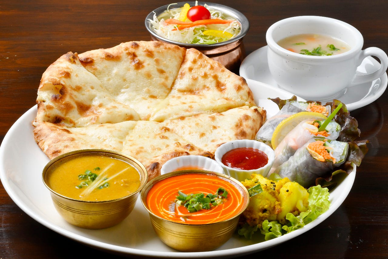 カレー、ナン、生春巻きなどのワンプレートランチが並んでいる様子