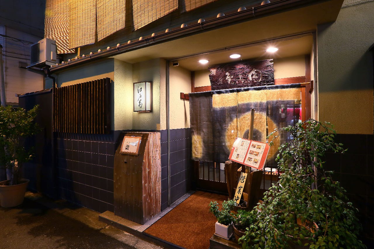 メニューボードと木彫り看板、のれんがかかっている江戸菊の玄関