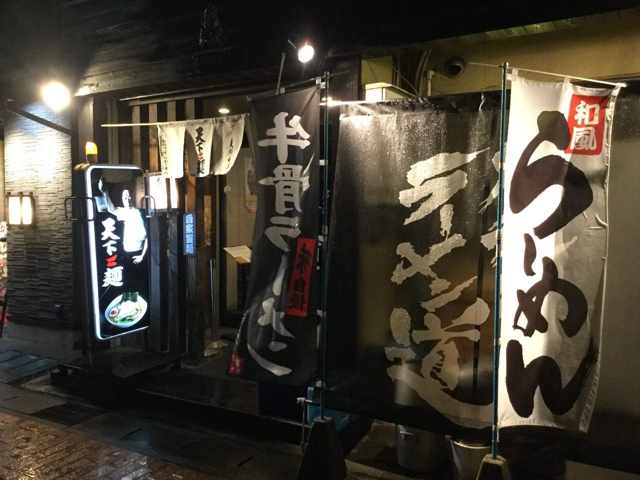 置き看板と垂れ幕、のぼり旗などがある天下ご麺大津店の外観