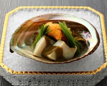 四角い皿にのった貝殻に料理が盛られている