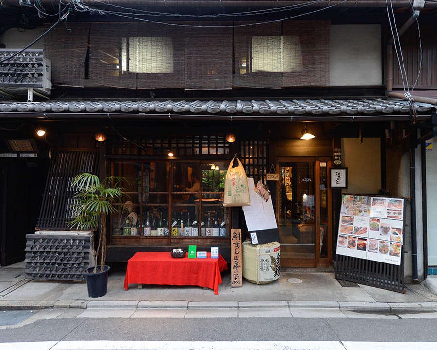 格子戸のある京町家とその前に置かれた長椅子や酒樽
