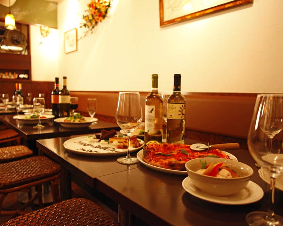 テーブルにワインやピッツァが並べているグランパ 中野サンモール店店内