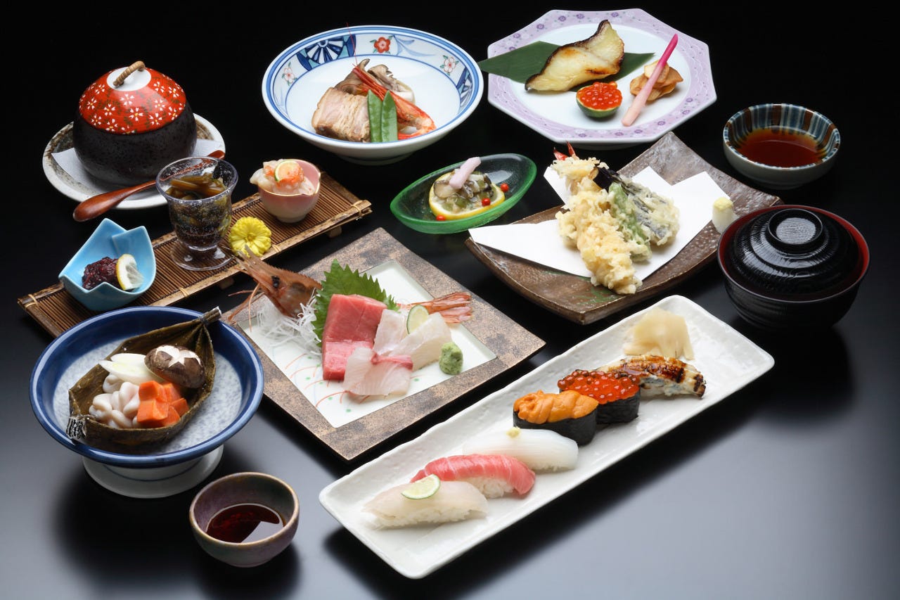 お寿司や天ぷら、焼き魚がお皿に盛り付けられて並んでいる