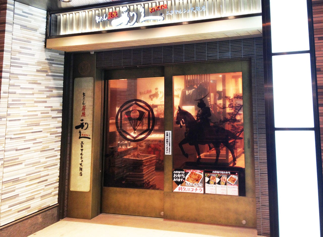 横長白色のネオンで店名が書かれた「牛たん炭焼 利久 エキマルシェ大阪店」の看板