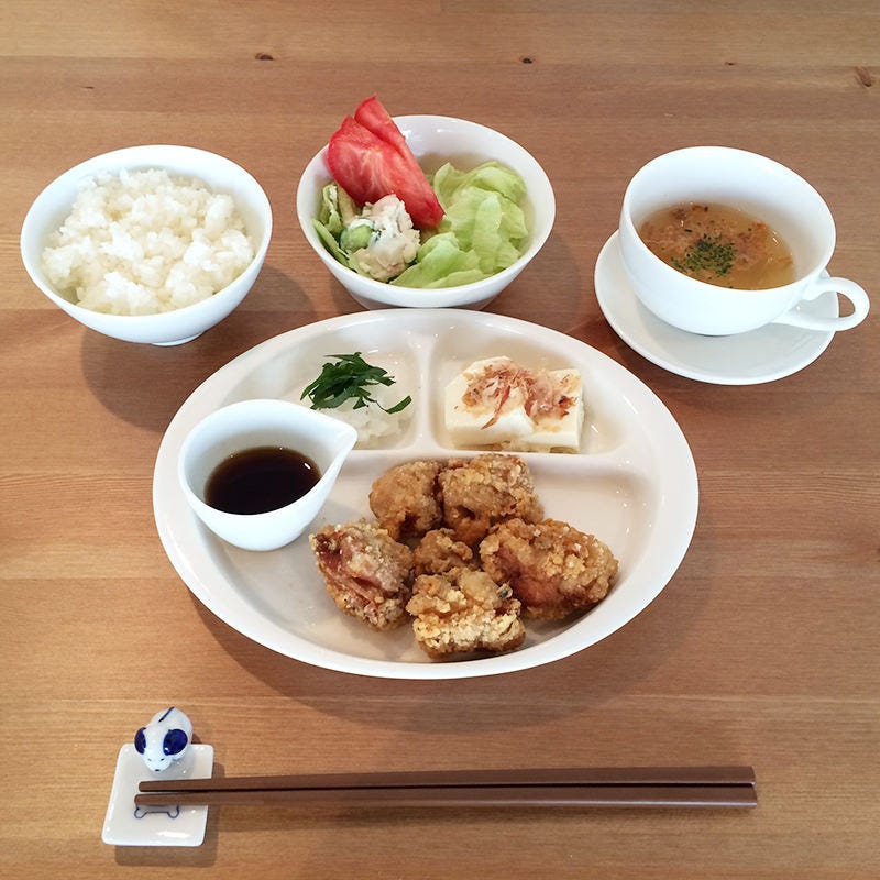 テーブルにおかれた竜田揚げのプレートとご飯、サラダ、スープ