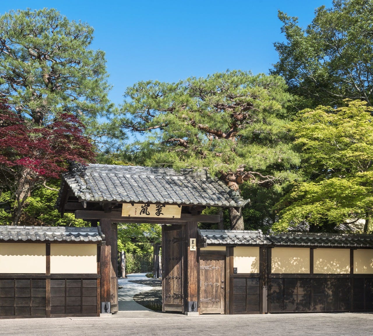 木に囲まれた日本邸宅の門と「茶寮 八翠」の看板