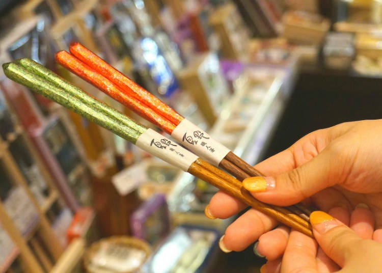 Produk asli “Sumpit bertabur emas”, sumpit kayu yang dibuat dengan teknik seperti proses pembuatan kain “Nishijin” dari Kyoto. Sumpit dengan motif bertabur emas dan perak yang tiada duanya, diwarnai dengan teknik pernis. (Harga 3.000 yen, belum termasuk pajak)