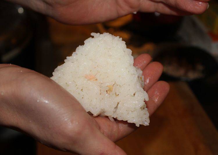 Put rice and filling on the chopping board, shape it into a triangle and do the finalization with your hands.