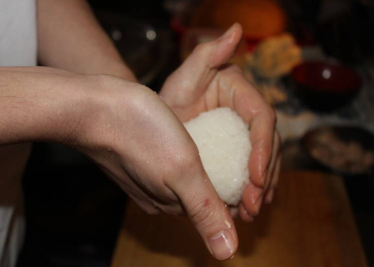 Wet your hands, add salt, and gently shape the onigiri.