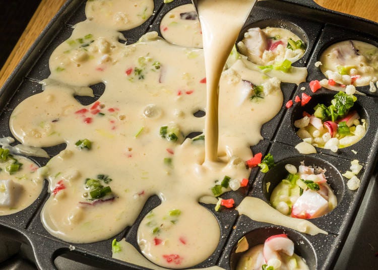 Takoyaki batter being poured into the mold for frying