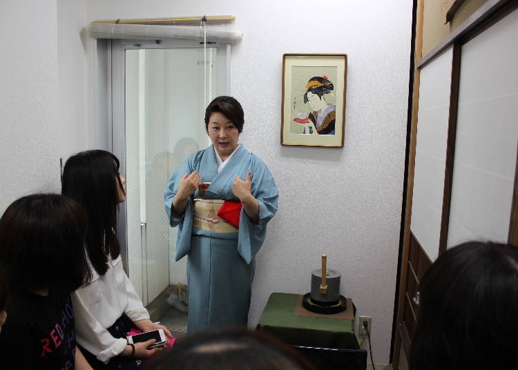 Ms. Takeda explains. The tool on her right is used to grind tea leaves.