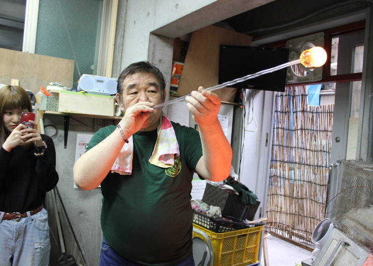 The master of the shop blowing a wind-bell. Three years of training are required to learn this craft.