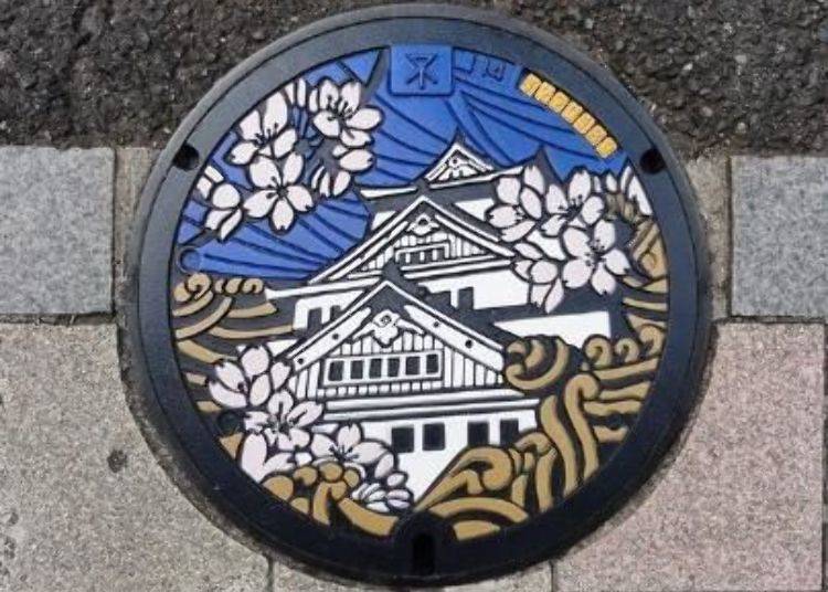 A manhole cover featuring the Osaka Castle, cherry blossoms and water current located in the south side of the main road of the Semba Shinsaibashi-suji Shopping District.