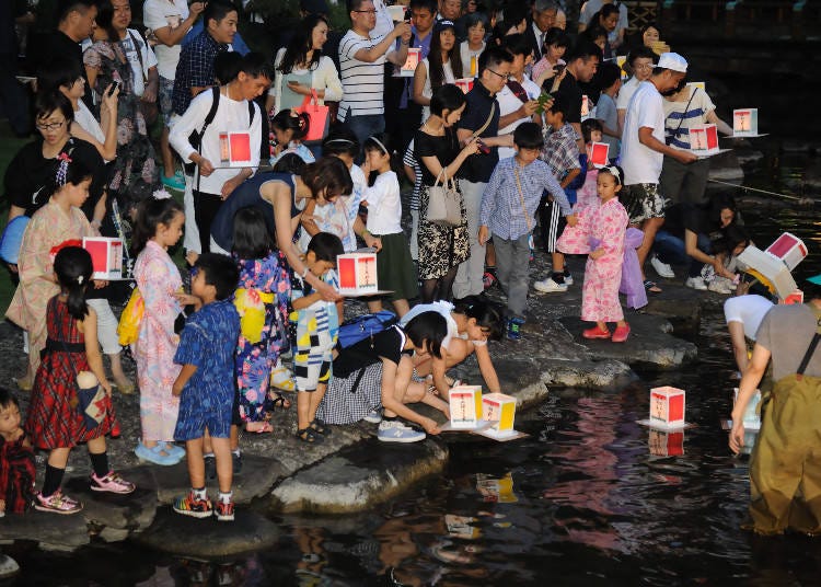 The moving scenery of floating paper lanterns on the nightly river.