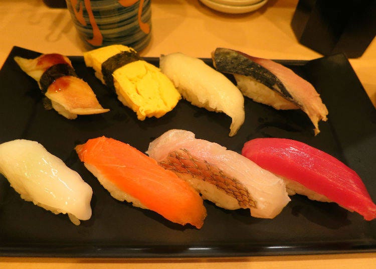 （左上起）星鰻、煎蛋、鰈魚鰭邊、醋醃鯖魚、（左下起）花枝、鮭魚、鯛魚、鮪魚。壽司配料隨著季節與進貨狀況而有所調整。