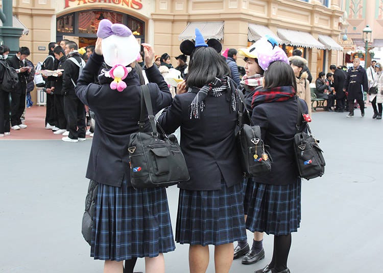 High school students enjoying Tokyo Disneyland in their uniforms