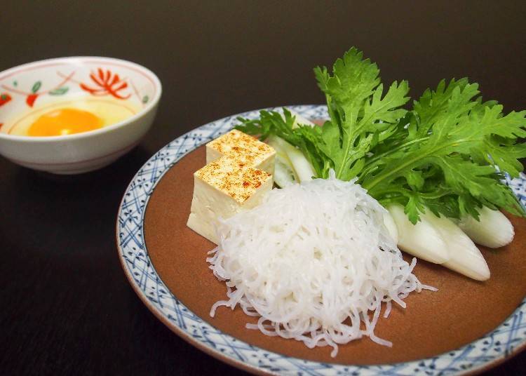 Tofu, konnyaku noodles, and edible chrysanthemum are stewed together before dipped in raw egg.