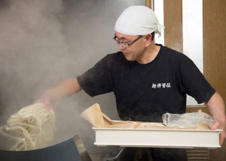 Mr. Miura expertly drops the udon noodles into the pot with precision and ease.