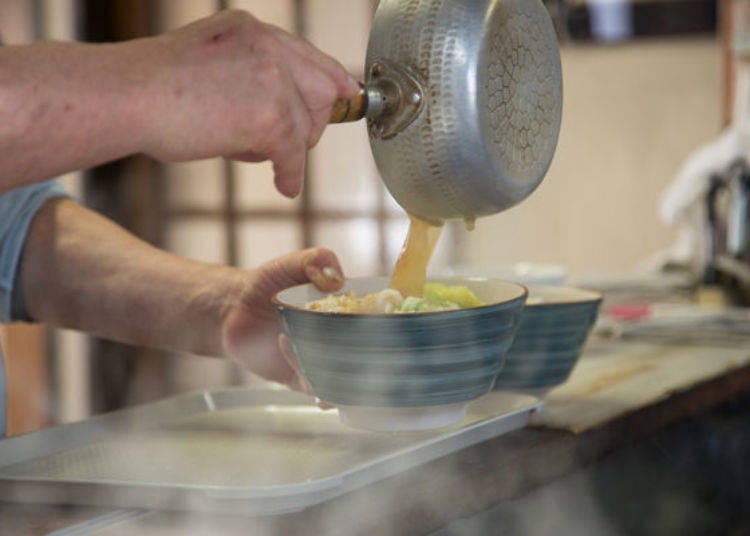 At the serving station, Tetsuo Watanabe carefully ladles the broth into each bowl.