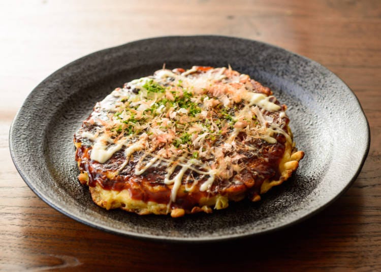 Okonomiyaki: A savory pancake packed with ingredients of choice, drizzled with a tangy sauce.