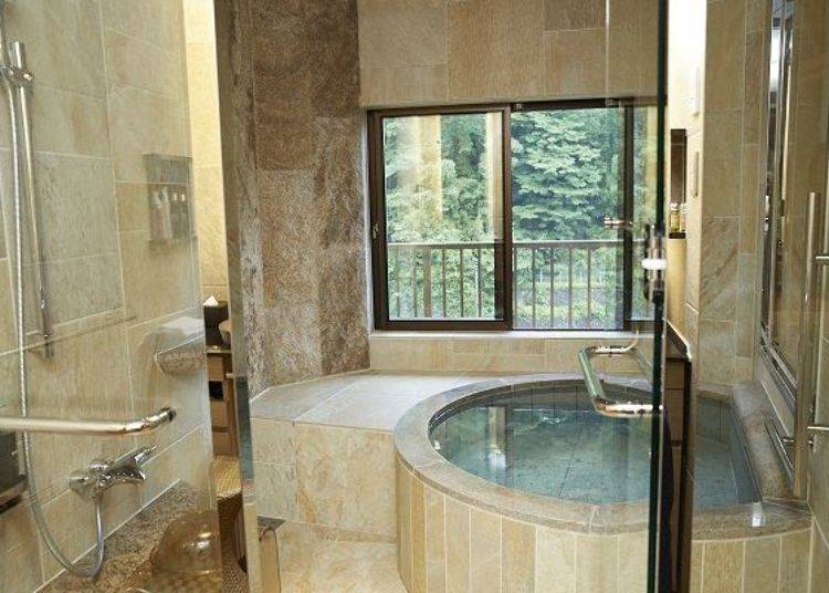 The elegant hot spring bath is made out of granite and boasts a view on the lush greenery just outside the window.