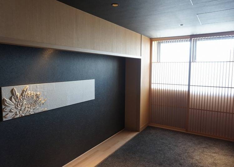 Right in front of the elevator lies an artwork of a chrysanthemum flower beside a sliding door.