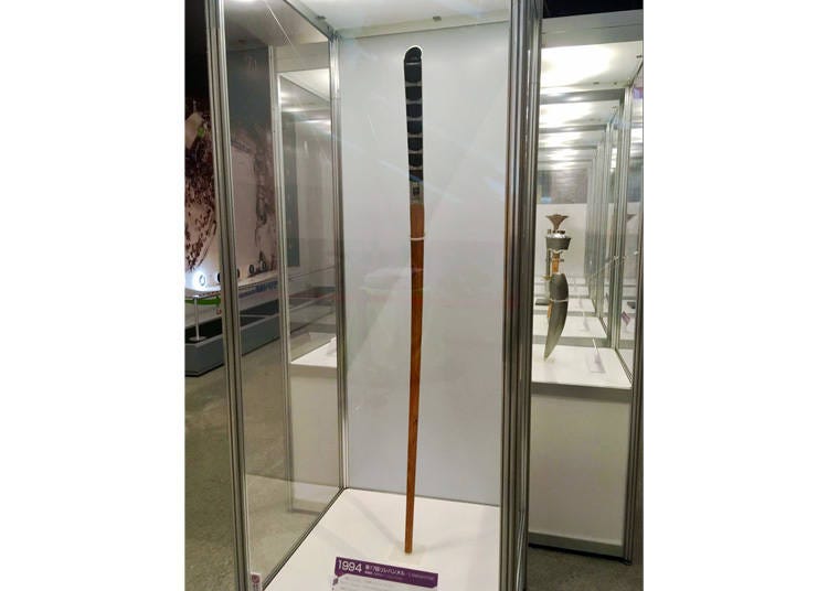 Multiple torches from past Winter Olympics sit on display, highlighting the unique qualities and size of each.