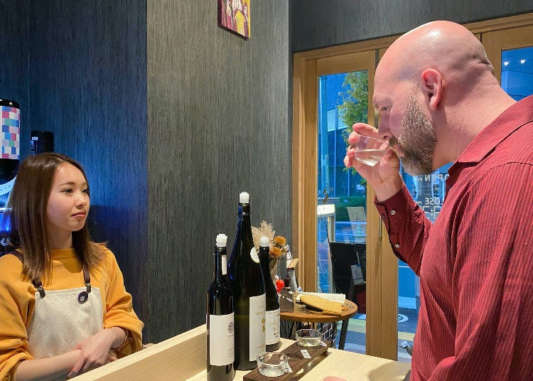 Timothy tasting the sake while talking sake with staff member Maria Sawayanagi