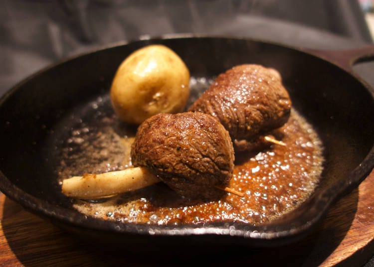 蝦夷鹿肉を骨に巻きつけたワイルドな「こんがり蝦夷鹿鉄板焼」（1,800円）は「wacca  from Hokkaido」で食べられる