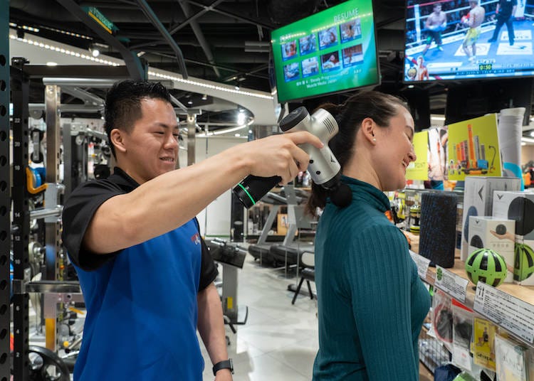 FITNESS SHOP staff shows customer how to use the HyperVolt.