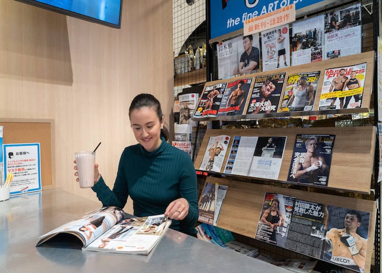 Customer enjoying a mixed-berry protein drink while flipping through some of the fitness magazines.