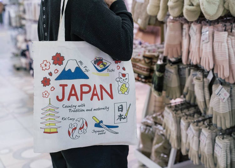 The tote bag has illustrations of cherry blossoms, Mt. Fuji, sushi, maneki neko, pagodas, and other cute images representing Japan