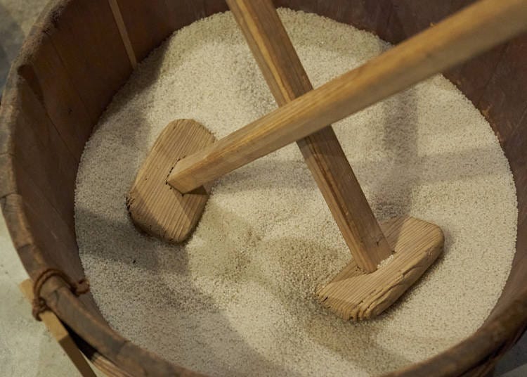In a technique called yamaoroshi, two workers use two flat paddles to crush the rice