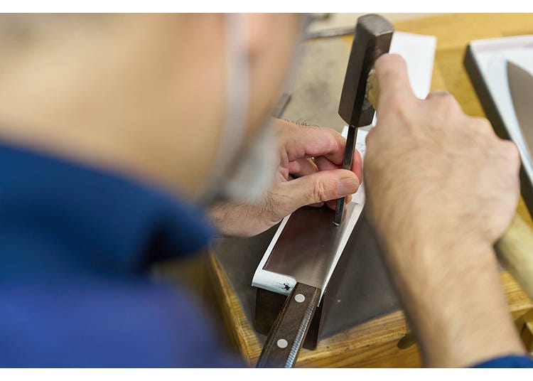 An engraver personalizes a knife using a hammer and chisel.