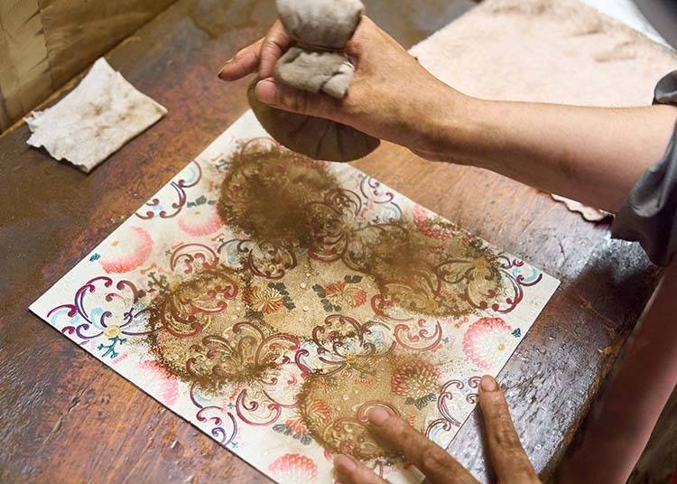 A careful process: artisans evenly coat the leather with finely ground makomo. Pattern: RANGIKU - Firework Chrysanthemums (Wine & Pink).