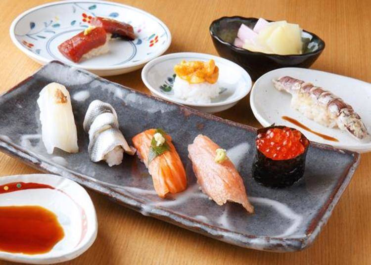 In clockwise order starting with the ikura (salmon roe), comes otoro (fatty tuna), sake (salmon), kohada (medium-sized gizzard shad), surume ika (squid), maguro no tsuke (pickled tuna), uni (sea urchin), and shako (mantis shrimp). In the upper right of the photo is a pickle garnish of fresh ginger, and yam pickled in shiso (beefsteak plant)