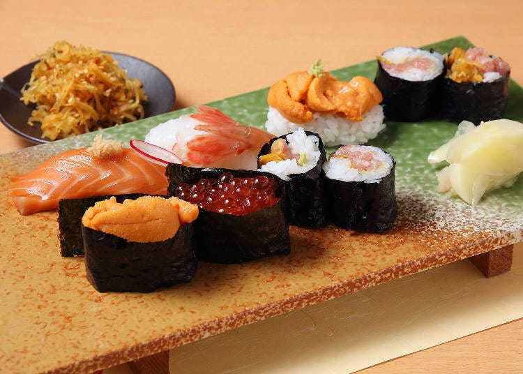 Front row, left to right: sea urchin gunkanmaki, salmon roe gunkanmaki, and torotaku (minced tuna and pickled radish roll). Middle row, left to right: salmon with yama-wasabi, botan shrimp, sea urchin with rock salt wasabi, and torotaku. The small plate on the upper left is torotaku-takuan (pickled torotaku).