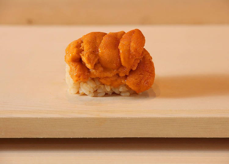 A beautifully arranged hand-roll stacked abundantly with sea urchin on top of rice. There seems to be even more uni than rice!