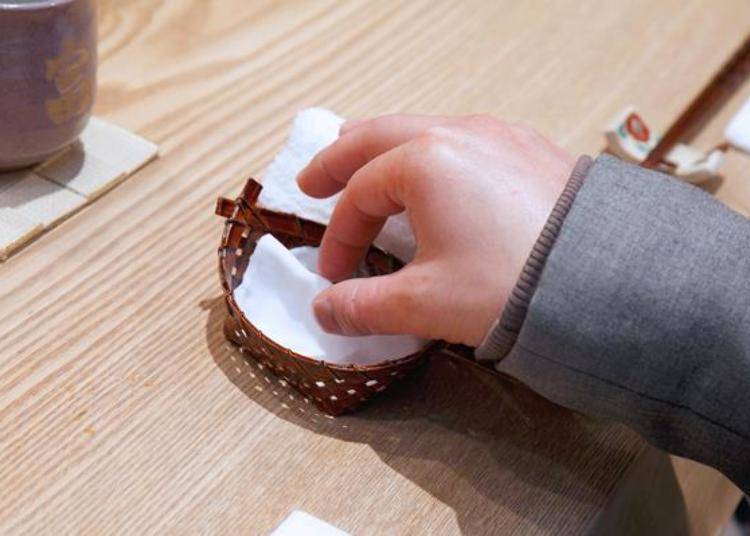 ▲可以将手在专门用来擦拭拿取握寿司指尖的湿毛巾上擦完用手拿着吃，也可以用筷子夹着吃。