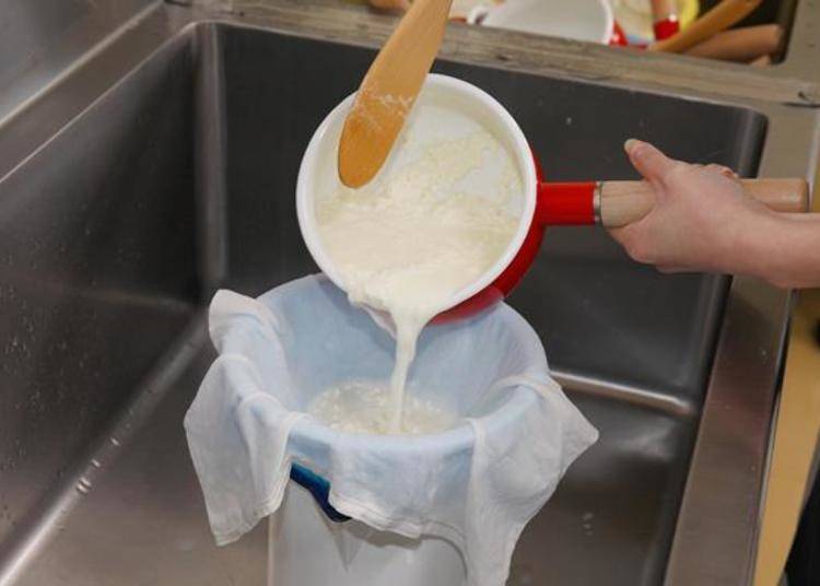 After stirring a few times with a wooden ladle, pour out the liquid (whey) into a wet cloth and take out the curds