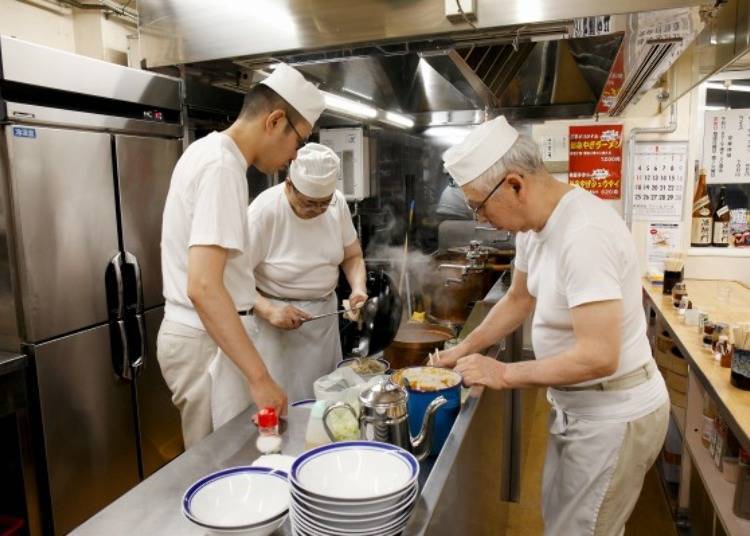▲To complete a serving a cup of ramen quickly, three cooks work in unison.