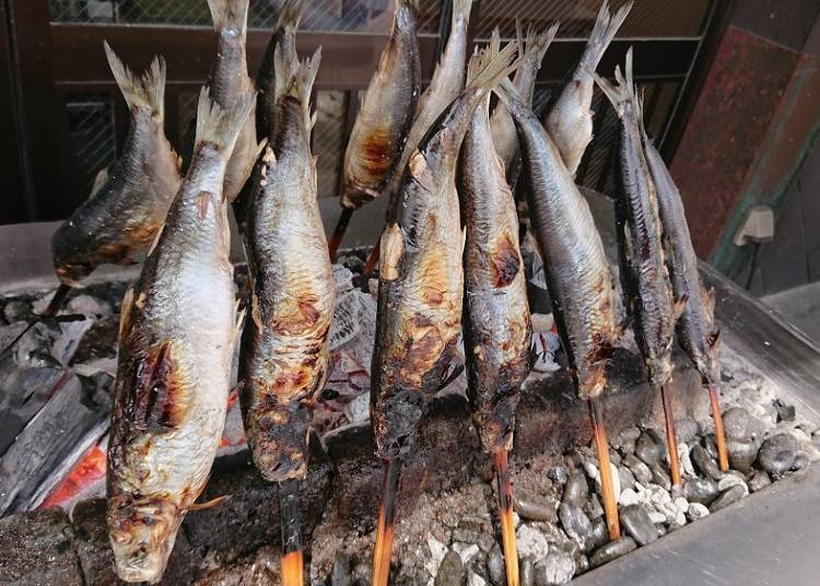 Herring being grilled over a bed of charcoal in front of the inn, filling the air with an inviting mouth-watering aroma