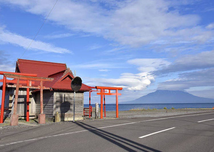 Minai Shrine faces the sea. The vermillion roof contrasts beautifully with the blue sky. Mt. Rishiri is visible far off in the distance.
