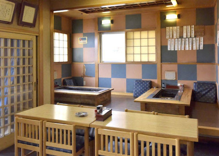 An interior view. Beyond the tables is a raised seating section (called koagari in Japanese) with robata (hearth) grills