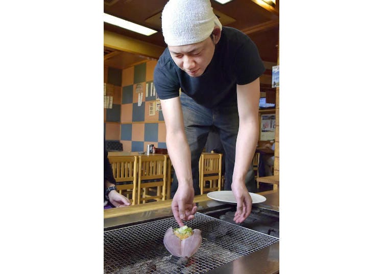 Mr. Nishioka placing a filleted Atka mackerel on the grill, skin side down