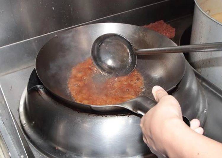The homemade soy sauce is stir fried in a large wok until it is almost burned