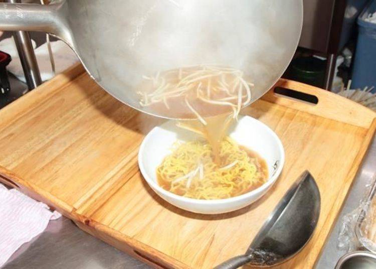 Once the noodles have been boiled they are put in a bowl and then the cooked soup and bean sprouts are poured over them.