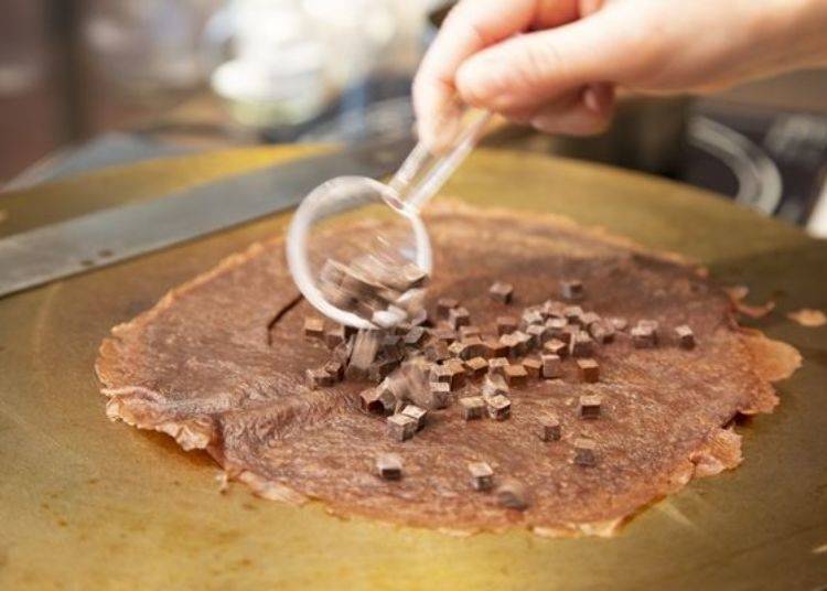 在LeTAO特製巧克力可麗餅的餅皮上，撒上巧克力小方塊後加熱製作。