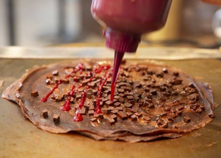 當巧克力小方塊開始融化時，快速淋上覆盆子果醬。