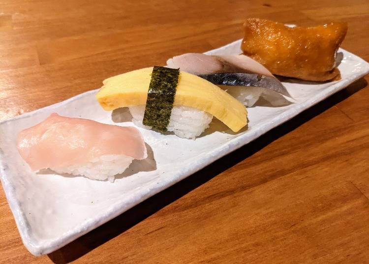 From the bottom left, nama hamu (dry-cured ham), tamago (egg), shime saba (pickled mackerel), inari (rice wrapped in sweet fried tofu)